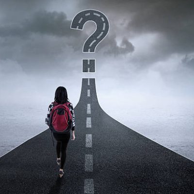 College student walking on the highway while looking at a question mark College student walking on the highway while looking at a question mark